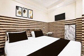 A hotel room with a bed, a TV, and a bathroom with a marble wall. - Deluxe With Twin Bed Ayush Villa (Kolkata)