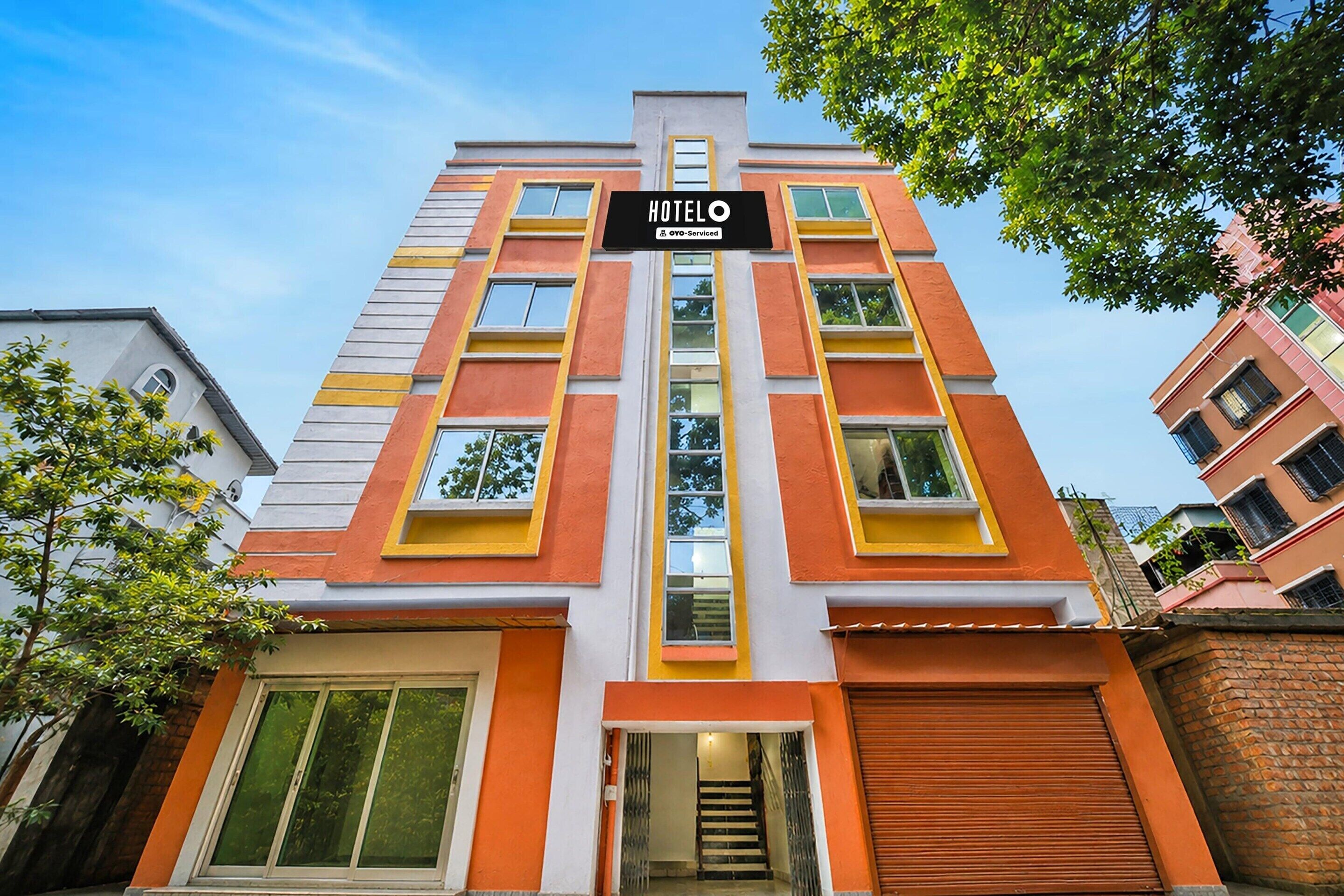 A multi-story hotel with a prominent 'HOTELO' sign, featuring a modern architectural design with orange and white color accents.