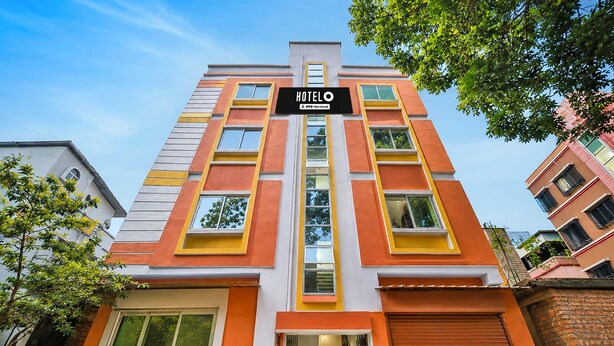 A multi-story hotel with a prominent 'HOTELO' sign, featuring a modern architectural design with orange and white color accents. - Deluxe With Twin Bed Ayush Villa (Kolkata)