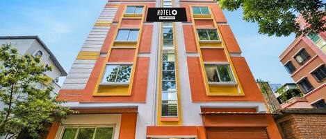 A multi-story hotel with a prominent 'HOTELO' sign, featuring a modern architectural design with orange and white color accents.