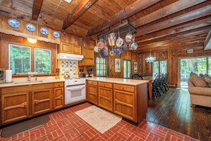 Une cuisine rustique avec des meubles en bois, un sol en briques et des casseroles suspendues.