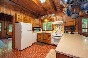 Eine Küche mit Holzschränken, einem Kühlschrank, einer Mikrowelle und einem Herd.