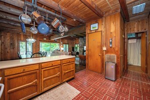 Une cuisine avec des meubles en bois, un réfrigérateur en acier inoxydable et des casseroles suspendues.