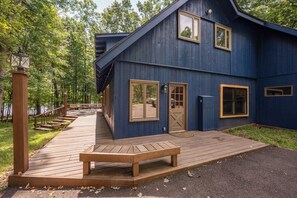 A wooden deck leading to a blue building with a door and windows. - New! Lake Front Home w/ Private Dock! (Swanton)