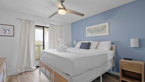 A bedroom with a bed, a ceiling fan, a nightstand, and a window with curtains. - Poolside Condo with Beach Access (Gulf Shores)