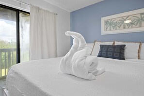 Ein Hotelzimmer mit einem großen Bett, Blick auf Grünfläche und einem Bild an der Wand.