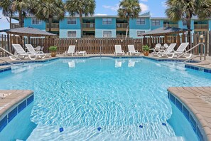 A clear swimming pool with lounge chairs and a wooden fence. - Poolside Condo with Beach Access (Gulf Shores)