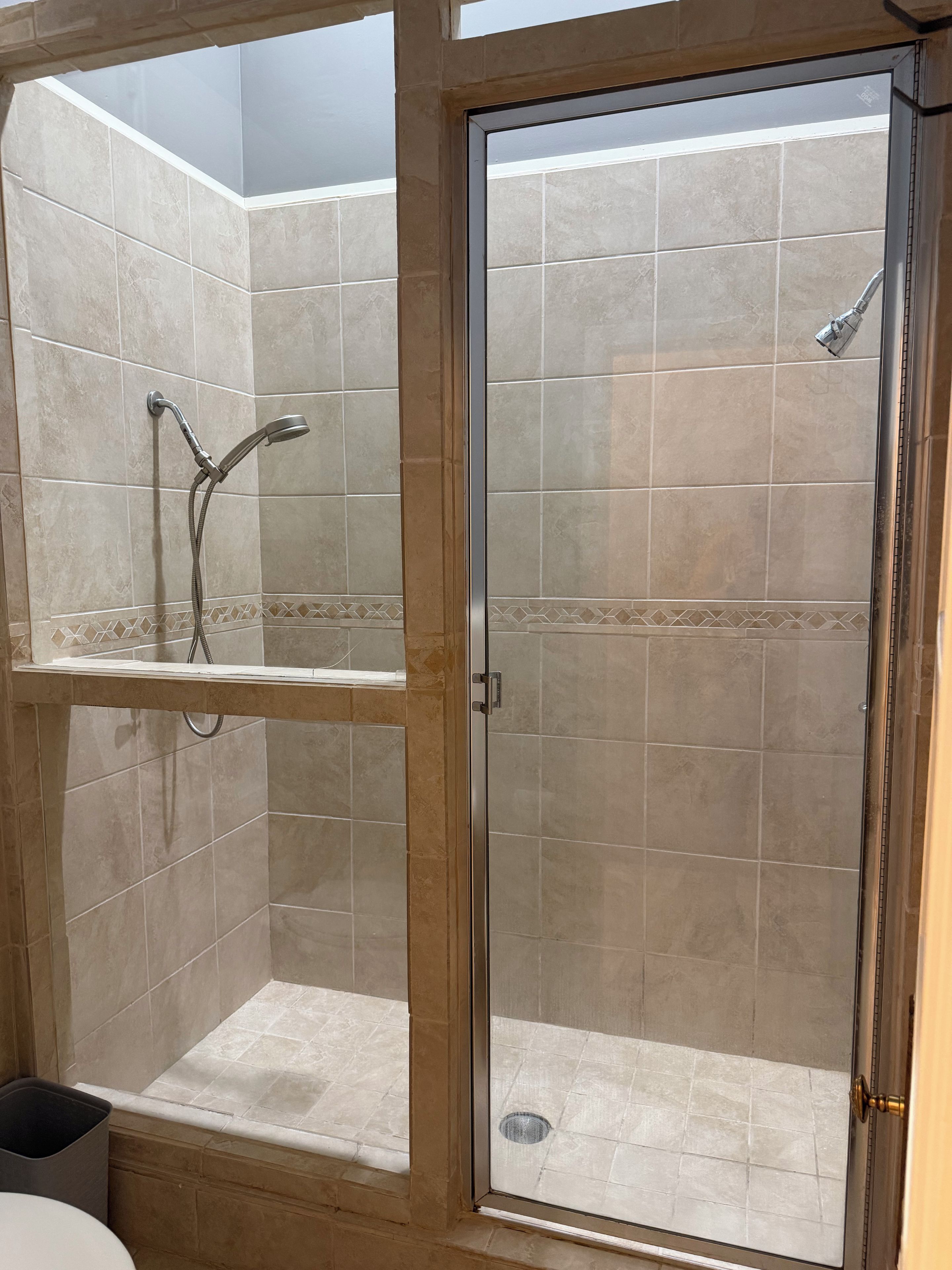 A bathroom with a glass-enclosed shower, a toilet, and a sink.