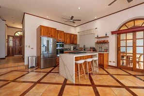 Eine geräumige Küche mit Holdekor-Schränken, einem Edelstahlkühlschrank und einer großen Kochinsel mit Barhocker.