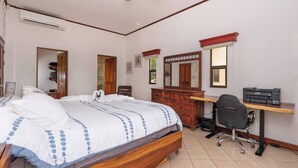 A bedroom with a bed, a desk, a chair, a dresser, and a mirror. - 3BR Retreat | Infinity Pool | Sunsets (Las Catalinas)