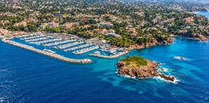 An aerial view of a marina with numerous boats docked, surrounded by residential buildings and a rocky coastline. - Apartment Le Mistral by Sur la mer (Saint Raphael)