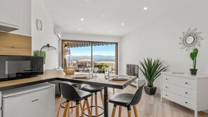 A modern kitchen with a dining area, a view of the sea, and a large window. - Apartment Le Mistral by Sur la mer (Saint Raphael)