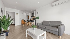 A modern living room with a grey sofa, a white coffee table, and a kitchen area in the background. - Apartment Le Mistral by Sur la mer (Saint Raphael)