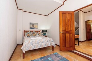 Une chambre à coucher avec un lit, un tableau, une porte en bois et un escalier.