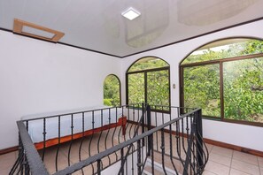 A room with a balcony, large arched windows, and a view of greenery outside. - 3 BR Home | Ocean Views, Sunsets, Pool in Paradise (Las Catalinas)