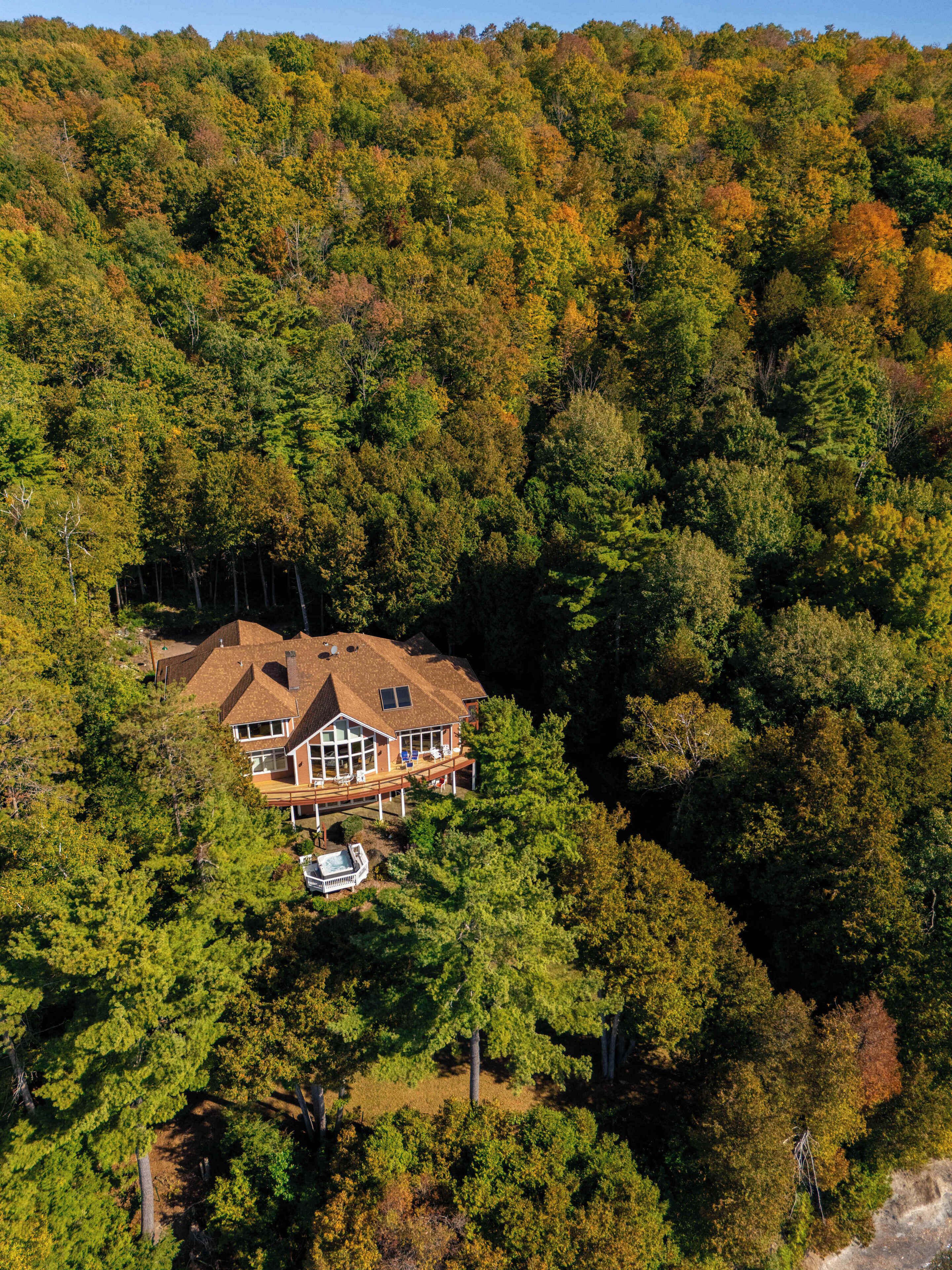 Ein großes Haus, umgeben von dichtem Wald, mit einem sichtbaren Swimmingpool.