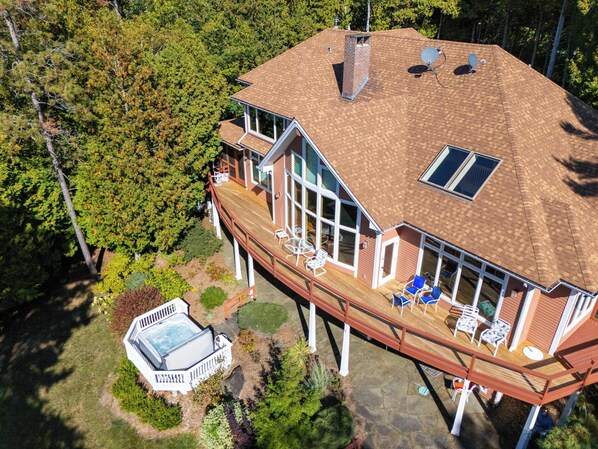 A large house with a deck, a hot tub, and a covered patio area.