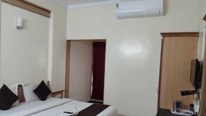Une chambre d’hôtel comprenant un lit, un bureau avec un ordinateur, un appareil de climatisation et une armoire.