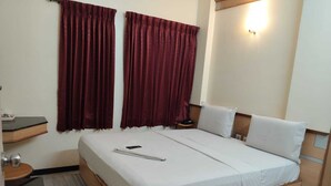 Une chambre d’hôtel comprenant un lit, une table de chevet, une chaise, une petite table et une lampe fixée au mur.