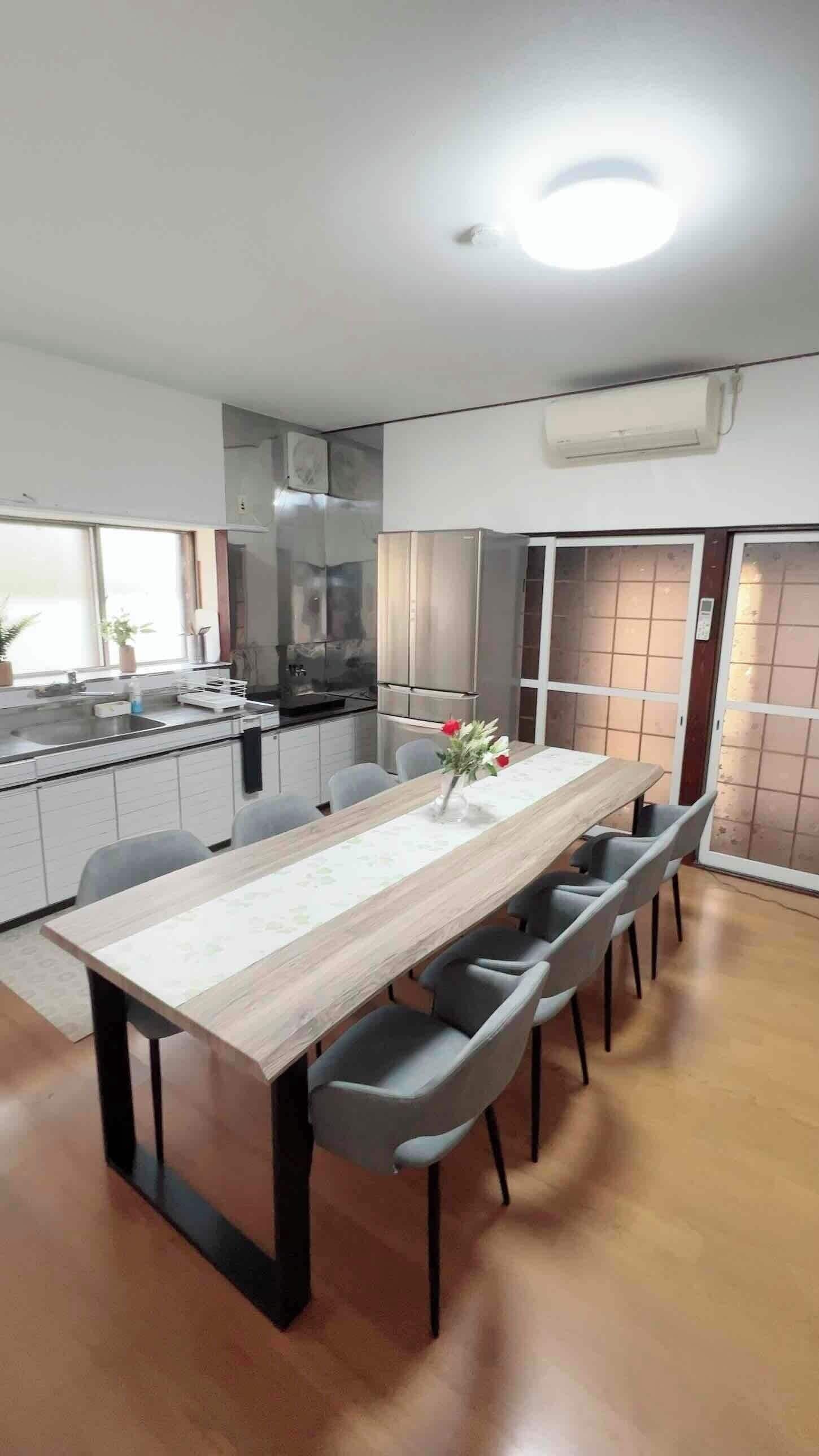 Une cuisine moderne avec un coin repas, comprenant une table en bois, des chaises grises et un four encastré.