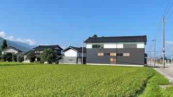A residential area with houses, a field, and a modern building with large windows.