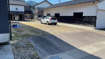 Una calle residencial con casas, un coche blanco estacionado y un cielo despejado.