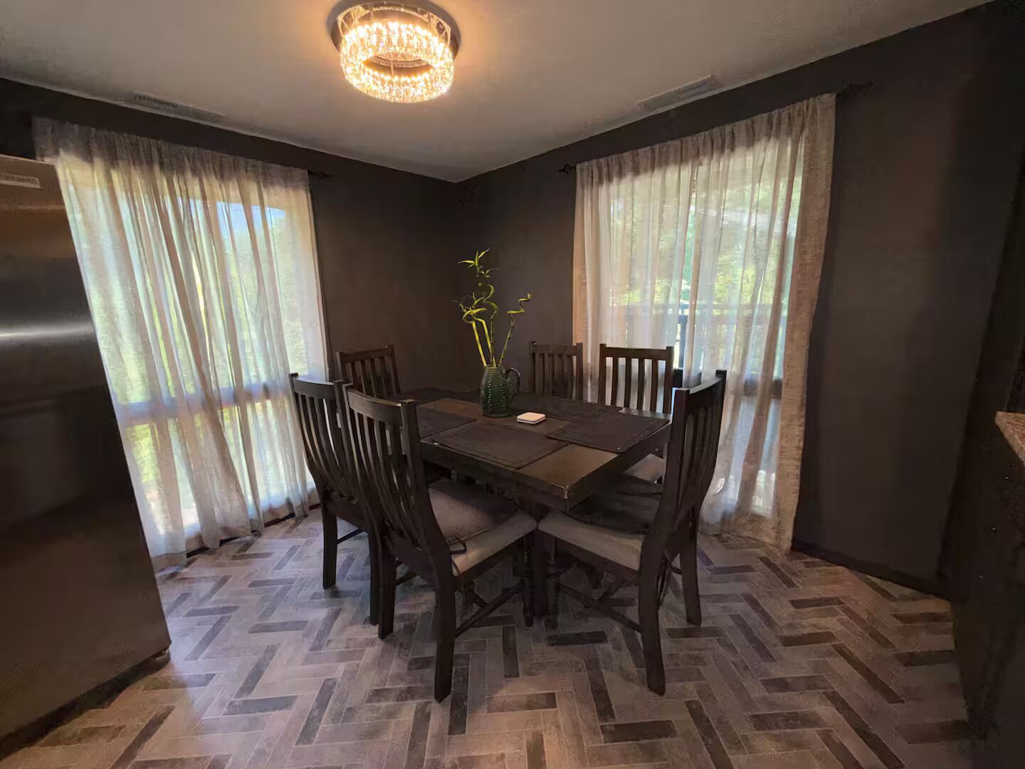 Un comedor con piso de diseño espiga y sillas alrededor de una mesa de madera.
