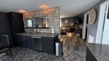 Uma cozinha moderna com parede decorada em pedra, eletrodomésticos embutidos e piso em padrão herringbone.