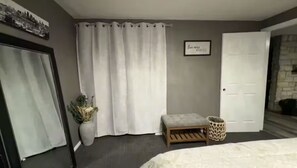 A bedroom with a bed, a bench, a potted plant, a door, and a wall with a framed quote. - KC Group Getaway - Spacious, Very Private - 14+ Ppl - Perfect for Chiefs games! (Independence)