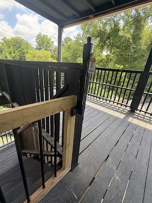 A wooden deck with a railing, a metal post, and a wooden handrail.