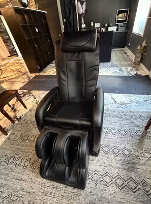 A massage chair with a footrest and a control panel.