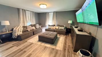 Una sala de estar moderna con un sofá modular, un reposapiés y un televisor de pantalla plana montado en la pared.