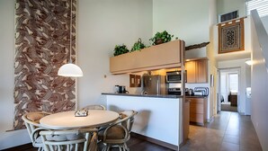 Uma cozinha moderna com área de jantar, apresentando uma ilha central, eletrodomésticos embutidos e um papel de parede estampado.
