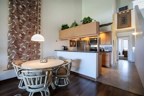 A modern kitchen with a dining area, featuring a central island, built-in appliances, and a patterned wall. - 4BR for 12, 2 Condos - Hale Kamaole, Kihei! (Kihei)
