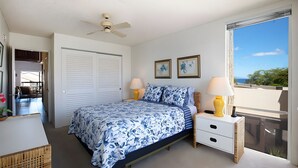 Quarto com cama, mesas de cabeceira, ventilador de teto e janela com vista.