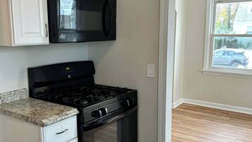 Una cocina con armarios blancos, un microondas negro y una estufa.