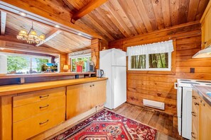 Eine Holzhütte mit einer Küche, inklusive Kühlschrank, Herd und Holzschränken.