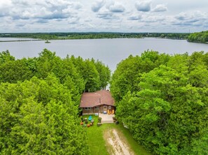 Ein Haus, umgeben von dichten grünen Bäumen, mit Blick auf ein großes Gewässer im Hintergrund.