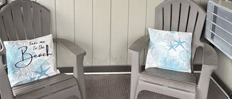 Two gray chairs with beach-themed pillows, a wall clock, and two signs reading 'MYRTLE BEACH' and 'LIFE IS A BEACH'.