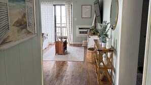 Een hal met houten vloer, een houten bankje, een spiegel aan de muur en een lijst met een afbeelding.