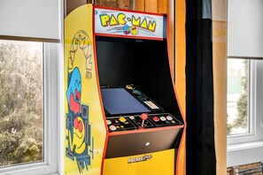 A Pac-Man arcade machine with a yellow and red color scheme, placed indoors near a window.