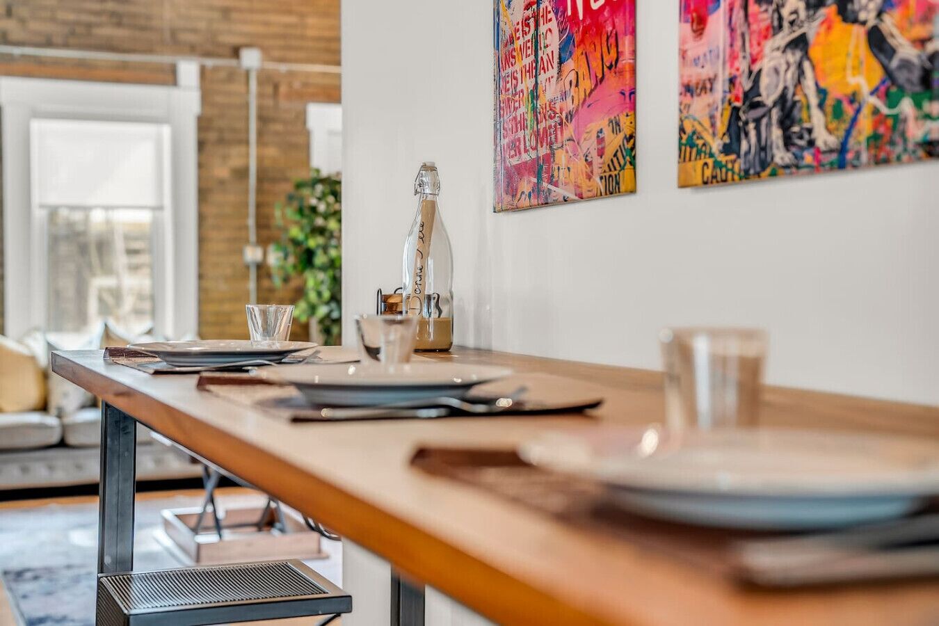 A dining area with a long table set for two, a bottle of water, and a glass on the table.