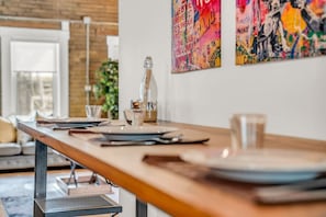 A dining area with a long table set for two, a bottle of water, and a glass on the table.
