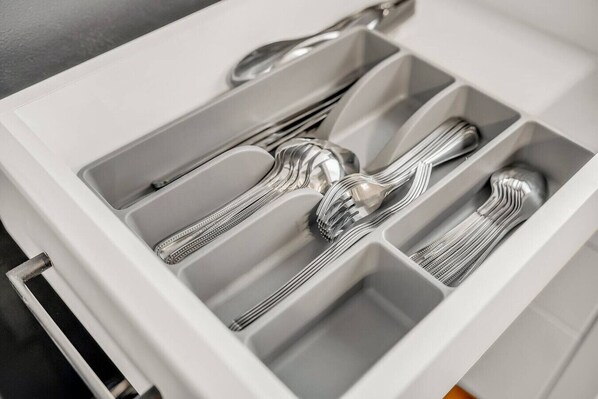 A drawer with multiple compartments, each containing a fork and a spoon.