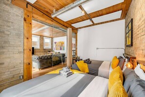 A modern bedroom with a bed, a sofa, and a dining area visible through an open door. - *Golden Loft*- RARE Downtown 2BR + Parking & Games (Toronto)