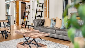 A modern living room with a chess table, leather sofa, and decorative shelves.