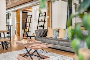 Una sala de estar moderna con una mesa de ajedrez, un sofá de cuero y estanterías decorativas.