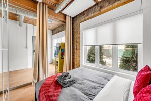 A modern bedroom with a large bed, a window with a view, and a wooden ceiling. - *Golden Loft*- RARE Downtown 2BR + Parking & Games (Toronto)
