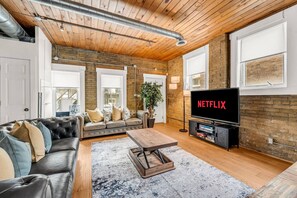 Ein modernes Wohnzimmer mit einem Ledersofa, einem Couchtisch und einem Fernseher, der 'NETFLIX' anzeigt.