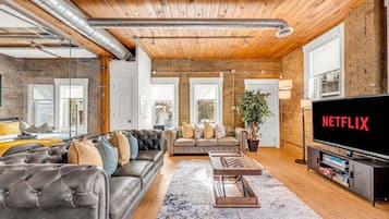 A modern living room with a leather sofa, a coffee table, and a flat-screen TV displaying 'NETFLIX'.